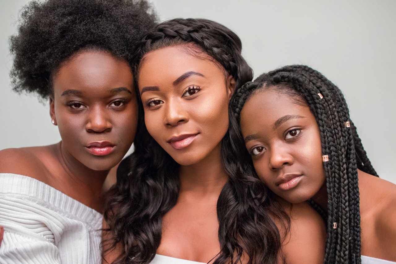 Three black women with natural hair, relaxed hair, and braids